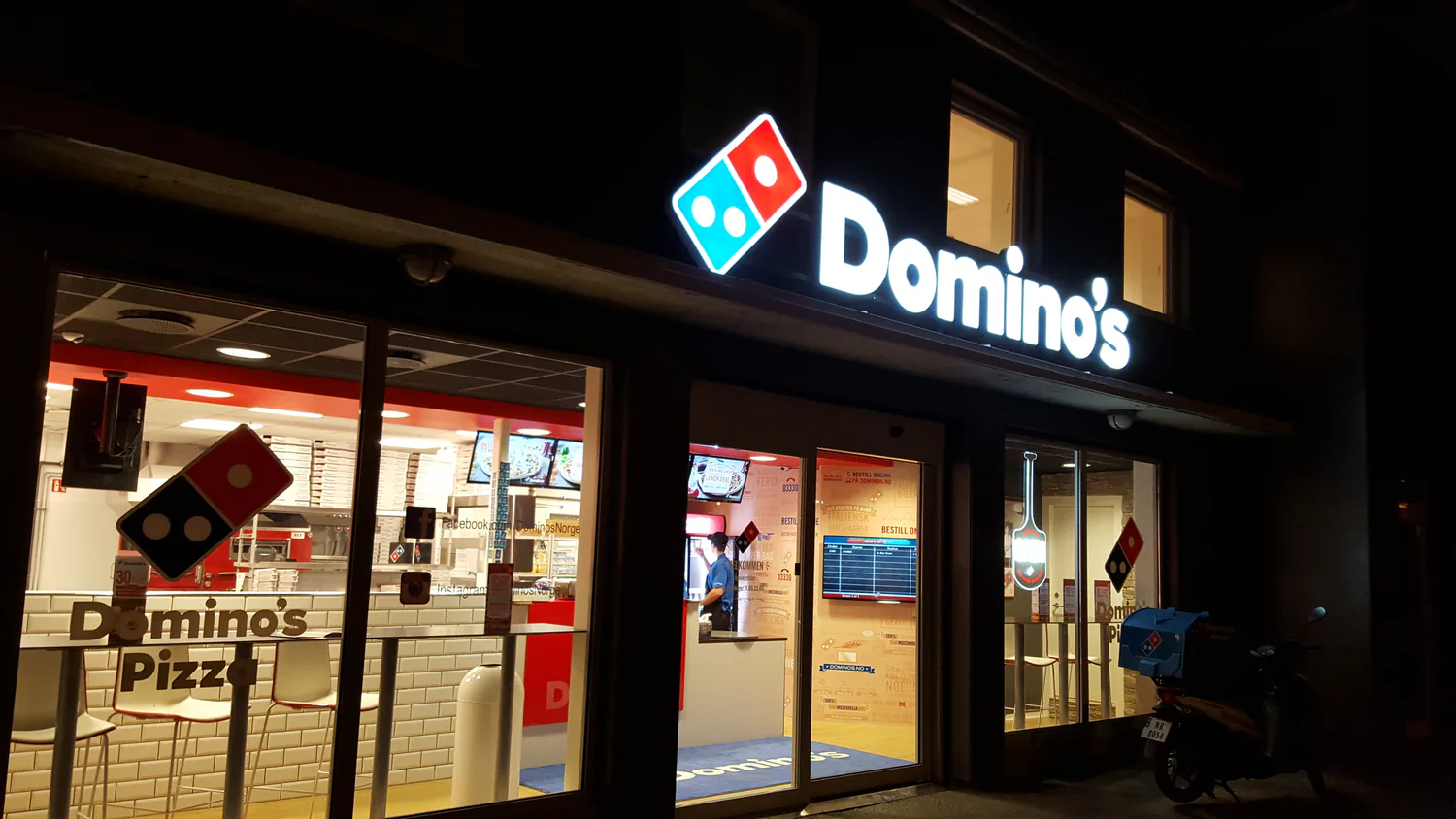 Domino's-butikk om kvelden med opplyst skilt over inngangen