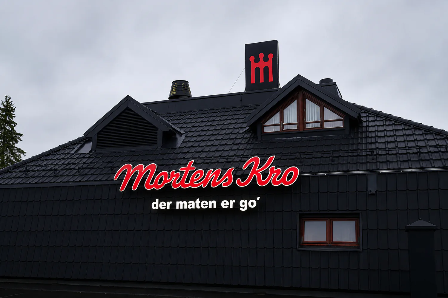 Mortens Kro i rød skrift og kronemerket på taket, mot grå himmel
